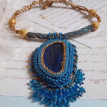 Pendentif Corsica avec un cabochon : une Agate Bleue brod&eacute;e avec des perles nacr&eacute;es Bleu Lapis en cristal &agrave; laquelle s&rsquo;ajoute des rocailles saphir et travertin entrelac&eacute;es pour former une dentelle